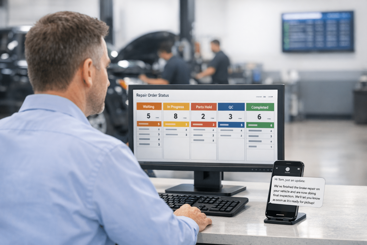 Service advisor in a dealership workspace checks a repair status dashboard while automated customer updates appear on a phone, with service bays active behind.