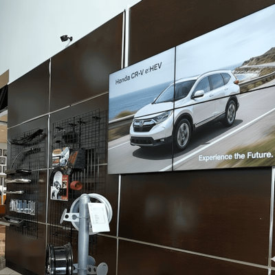 Large dealership showroom video wall displaying vehicle features, promotions, and digital leaderboards.